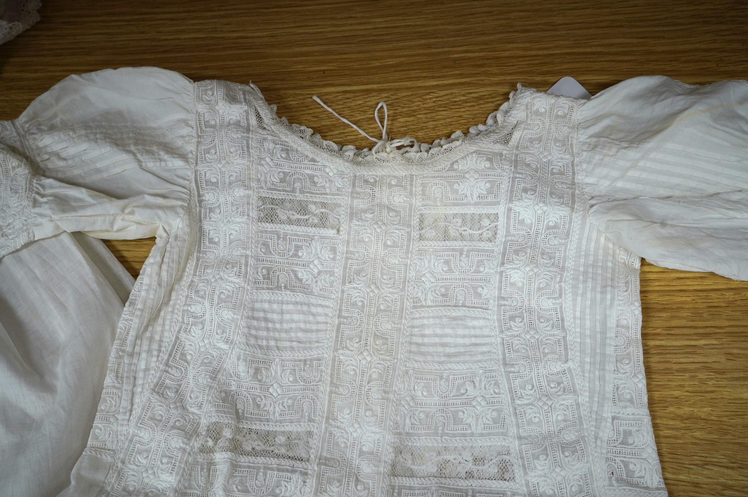 Two unusual 19th century intricately white worked children’s dresses, one hand worked with fine panels of white work, feather stitching and tucking, edged and inserted with hand made Valenciennes lace, the other worked i